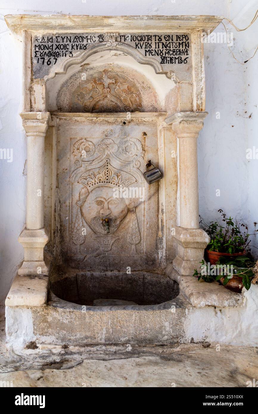 Historischer, reich verzierter Steinbrunnen mit griechischem Text und dekorativen Details, Mykonos, Griechenland Stockfoto