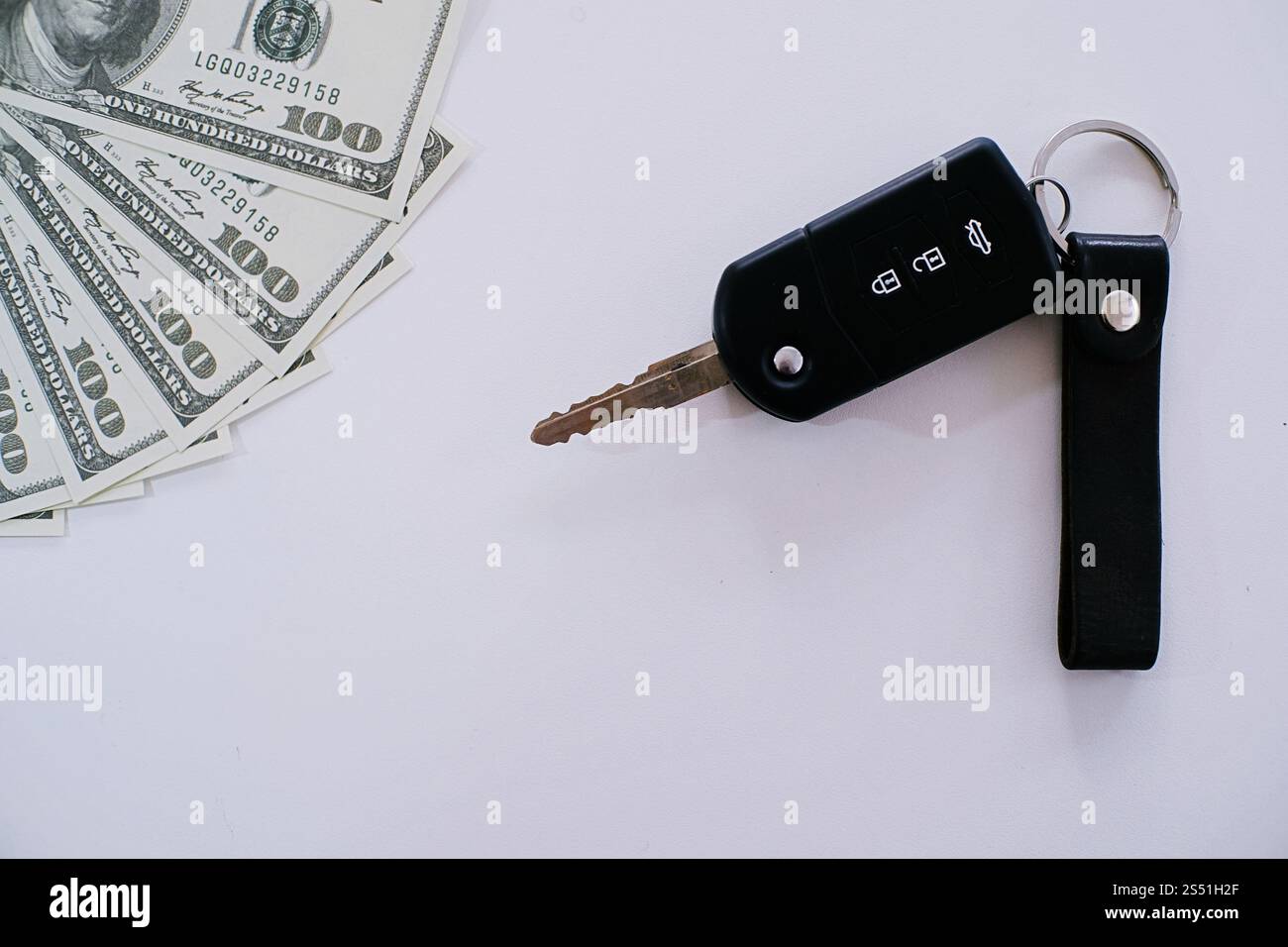 Autoschlüssel auf 100 Dollar mit weißem Hintergrund Stockfoto