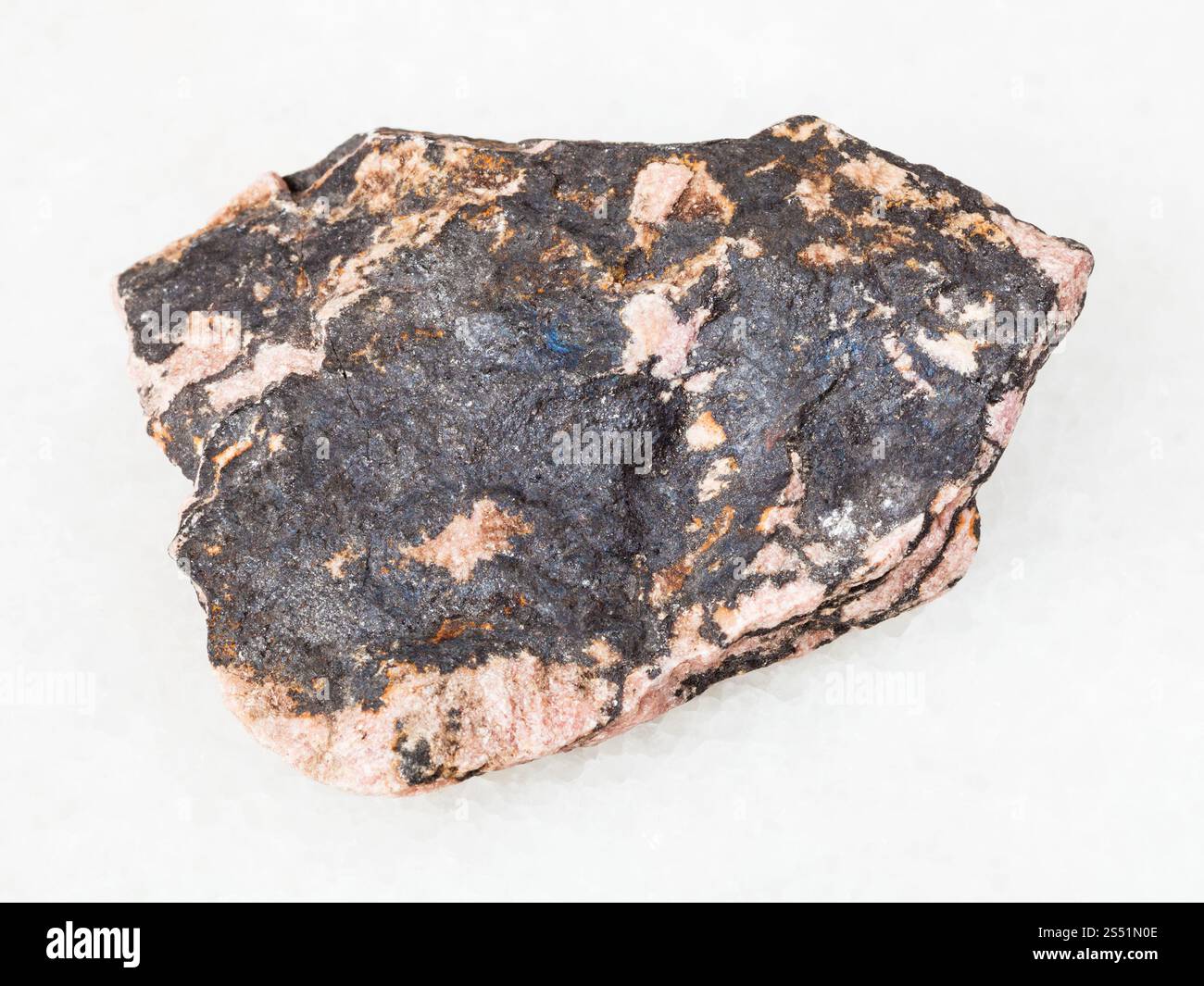 Makroaufnahmen von natürlichen mineralischen Rohstoffen Rhodonit Stein auf weißem Marmor aus Ural Stockfoto