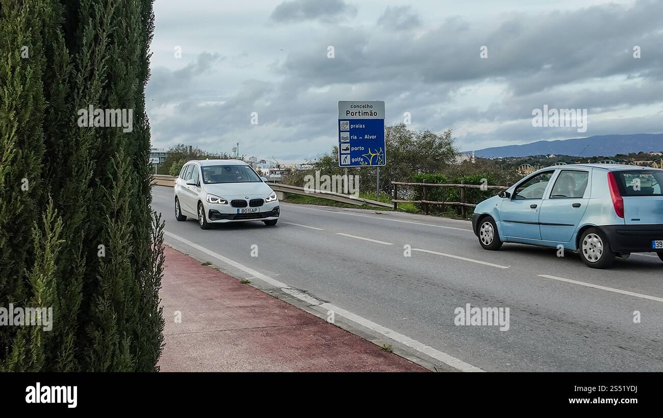 Ein Straßenschild, das nach Portimão führt, befindet sich direkt an der Straße, an dem Autos vorbeifahren. Stockfoto