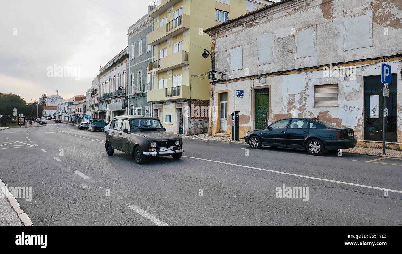Eine Straßenszene in der Stadt Parchal, Portugal, mit alten Autos, die entlang der Straße fahren. Im Hintergrund sind alte Gebäude zu sehen, von denen einige anmutig sind Stockfoto