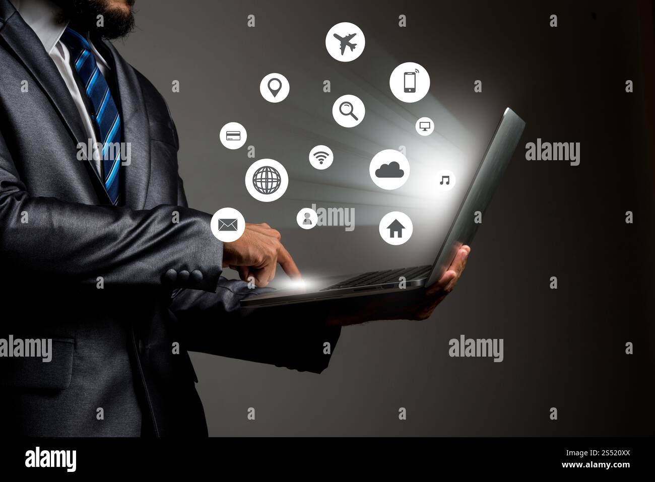 Geschäftsmann mit Multimedia-Icon-Schnittstelle auf Laptop konzeptionell. Geschäftsmann mit Multimedia-Icon-Schnittstelle auf Laptop-Konzeptbild von Social Media Stockfoto