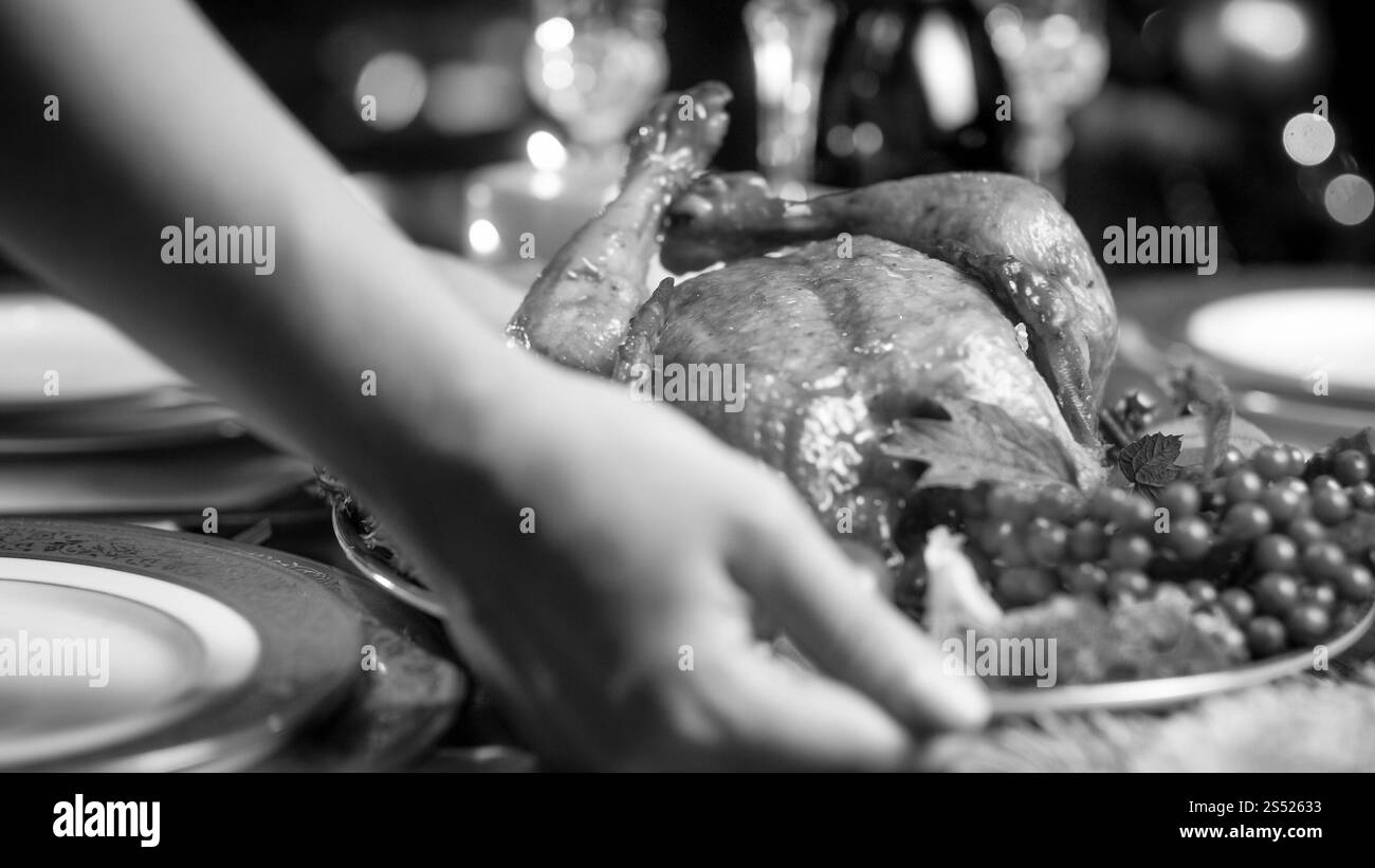 Nahaufnahme Foto von einer jungen Frau, die gebackenes Hühnchen auf den Esstisch legt, der zum Weihnachtsessen serviert wird. Nahaufnahme von einer jungen Frau, die gebackenes Hühnchen auflegt Stockfoto