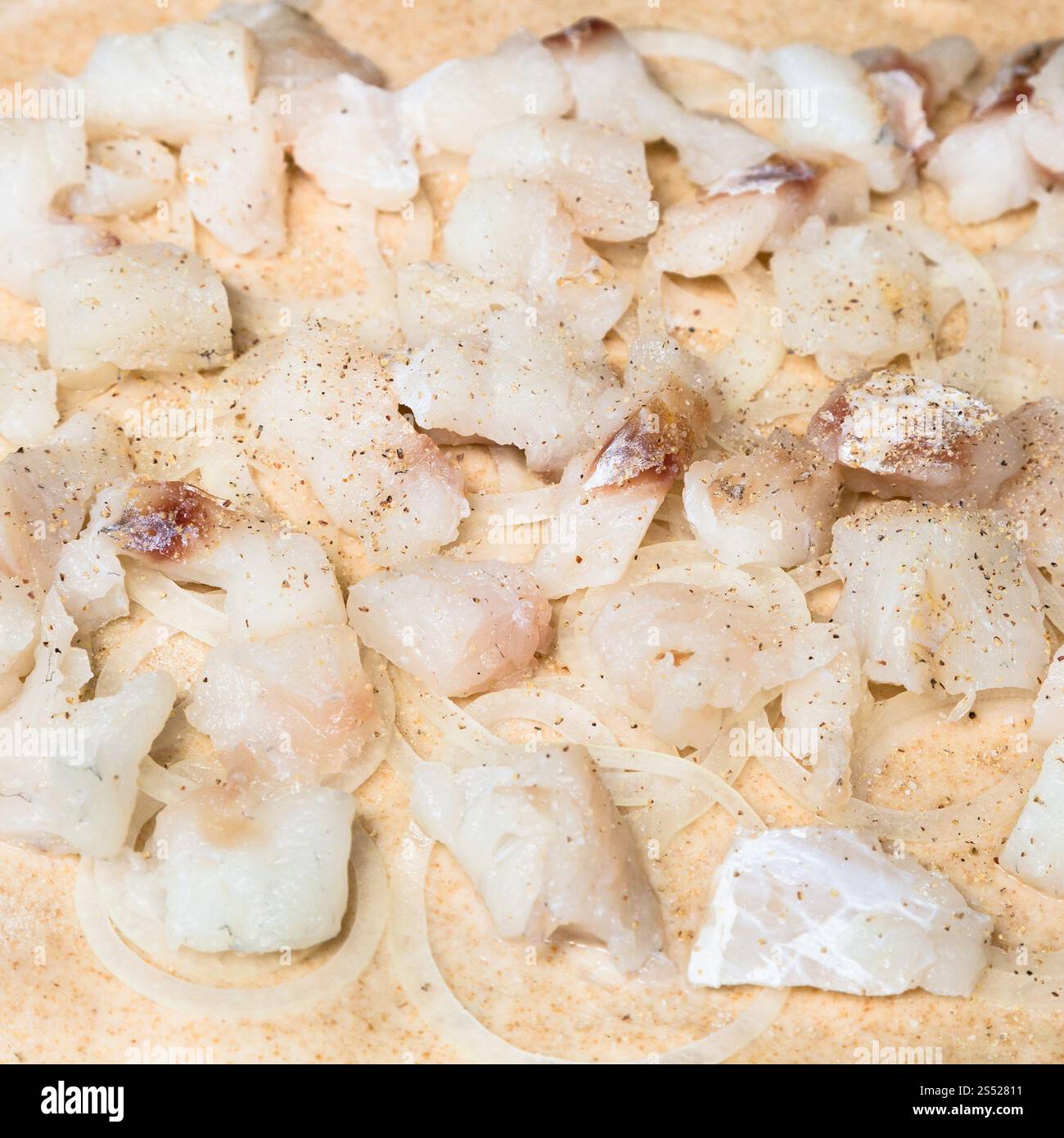 Kochen von Pie-Füllung aus rohem Fisch und Zwiebeln auf Teig Stockfoto