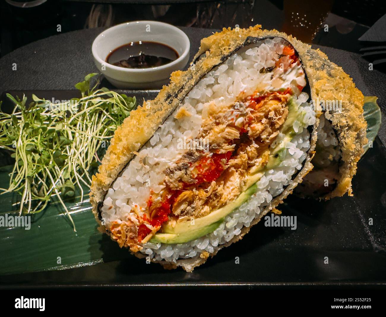 Sushi-Burger mit Lachs, Avocado, Salat und Reis in Nahaufnahme auf einem Teller Stockfoto