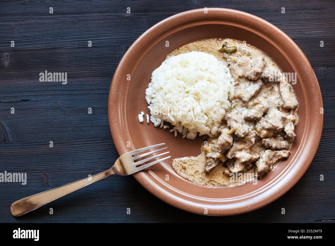 Russische Küche: Zubereitete Portion Rindfleisch Stroganoff (Rindfleisch Stroganow, Befstroganov) Fleischstücke in Sauerrahm mit gekochtem Reis Stockfoto