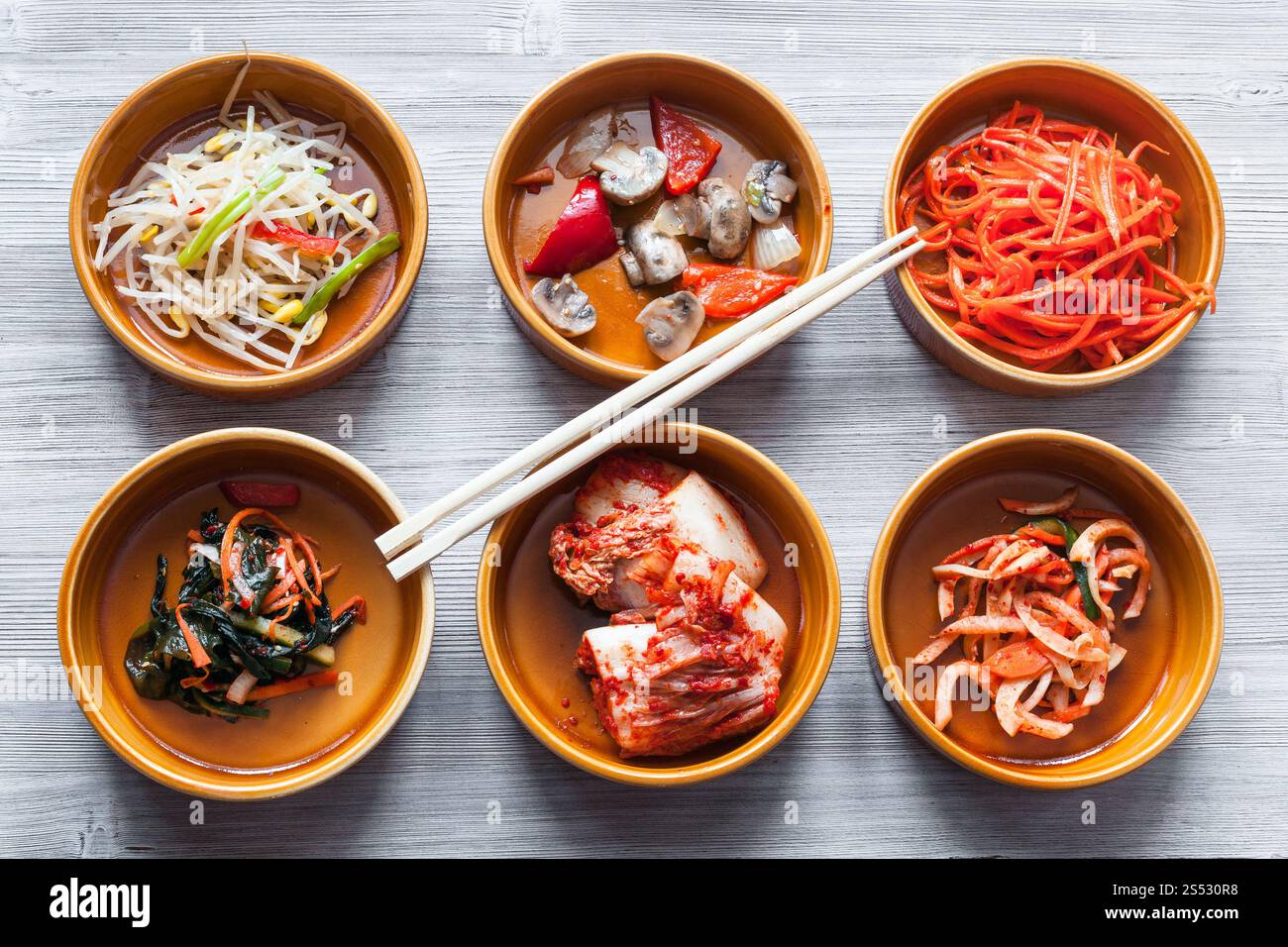 Die koreanische Küche - essstäbchen auf Schüsseln mit verschiedenen Beilagen (Banchan oder panchan) auf Graue Tabelle Stockfoto