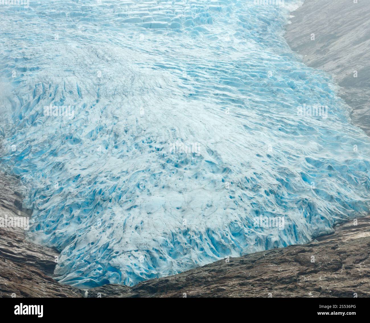 Blick auf den Svartisen-Gletscher von der Seite des Sees Svartisvatnet (Meloy, Norwegen). Kleine, nicht erkennbare Menschen sind weit in der Nähe des Gletschers. Stockfoto