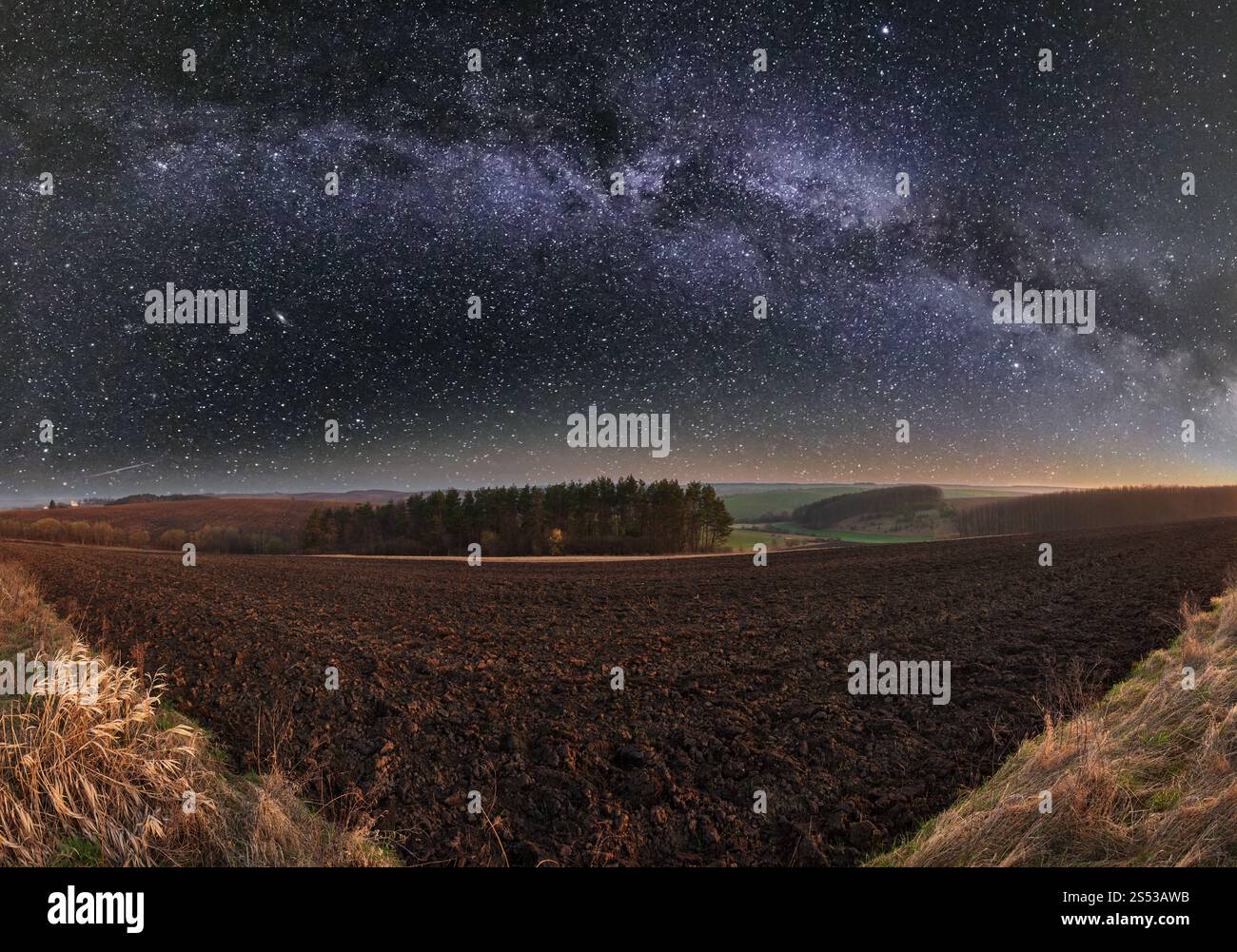 Der frühe Frühling Nacht ländliche Landschaft mit Gepflügt landwirtschaftliche Felder auf Hügel, Olivenhaine und das Dorf Stadtrand in weit. Ackerbau und Wachstum Ackerland Stockfoto