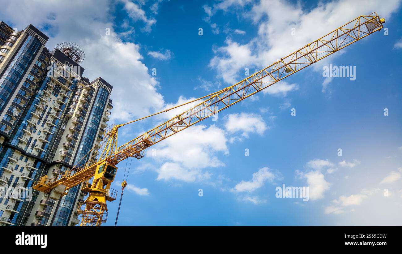 Foto eines Hochbaukrans auf der Baustelle vor blauem Himmel und Wolkenkratzern. Bild des Hochbaukrans auf der Baustelle gegen Blau Stockfoto