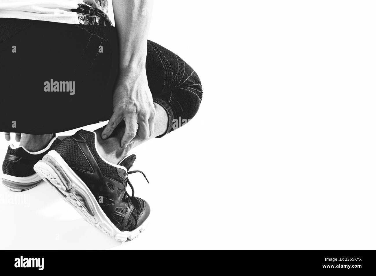 Läufersportler mit Schmerzen am Knöchel mit gebrochenem, verdrehtem Gelenk, Laufsportverletzung und Athletischer Mann, der den Fuß aufgrund einer Verstauchung berührt, schwarz-weiß Stockfoto