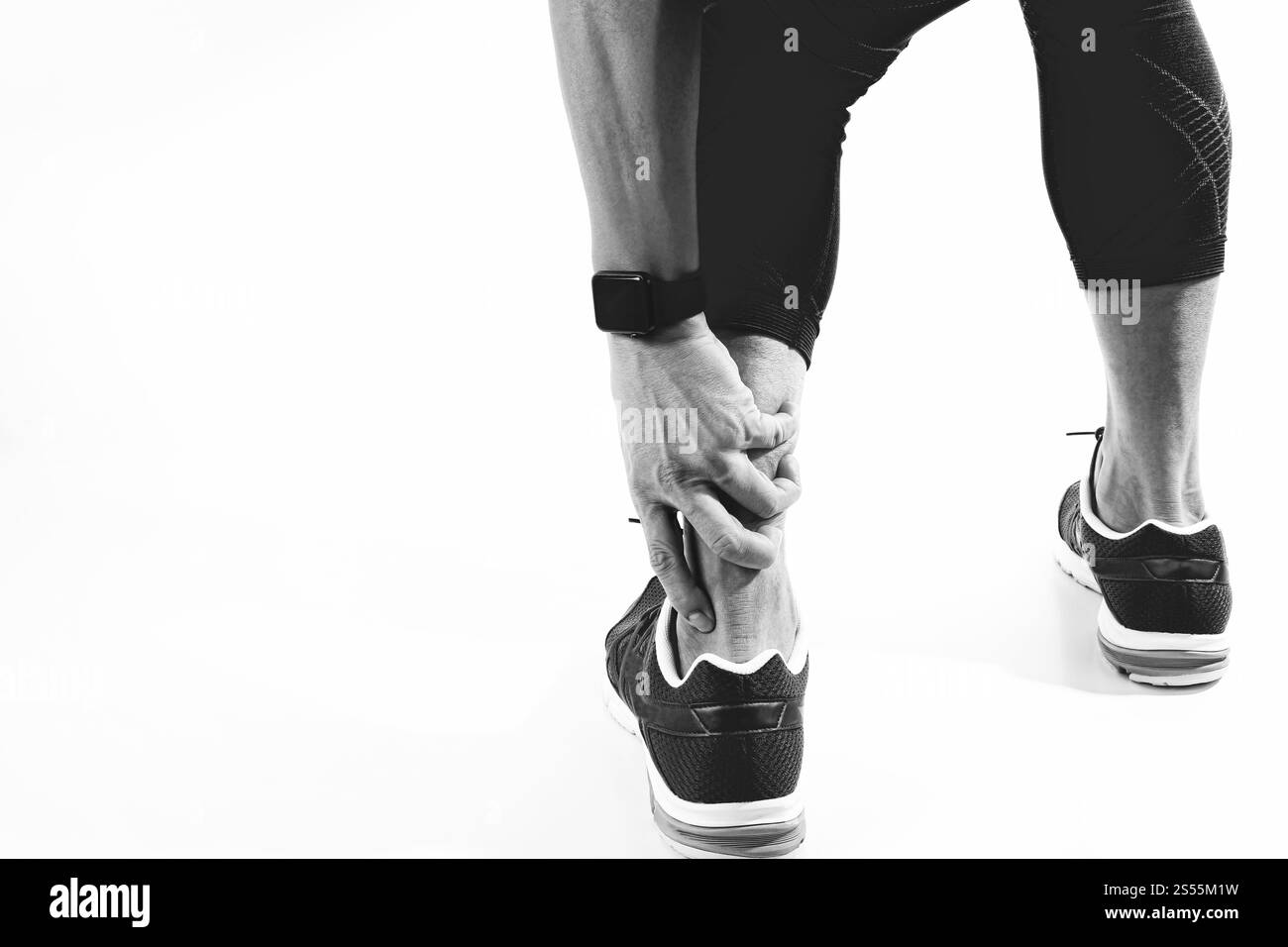 Läufersportler mit Schmerzen am Knöchel mit gebrochenem, verdrehtem Gelenk, Laufsportverletzung und Athletischer Mann, der den Fuß aufgrund einer Verstauchung berührt, schwarz-weiß Stockfoto