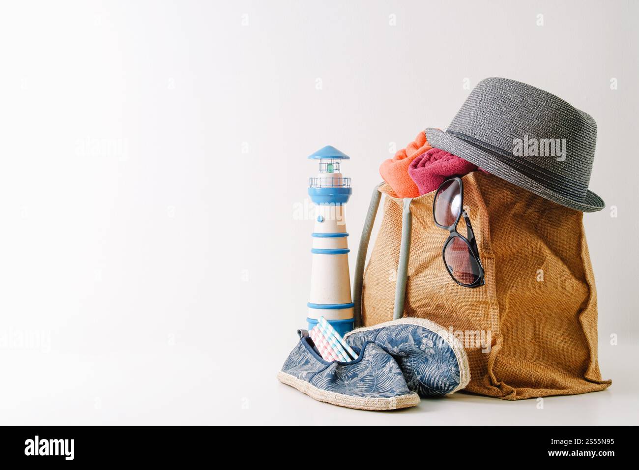 Reisekonzept für Sommerurlaub. Hipster-Strandtasche mit Artikeln für einen Tag am Meer auf weißem Hintergrund Stockfoto