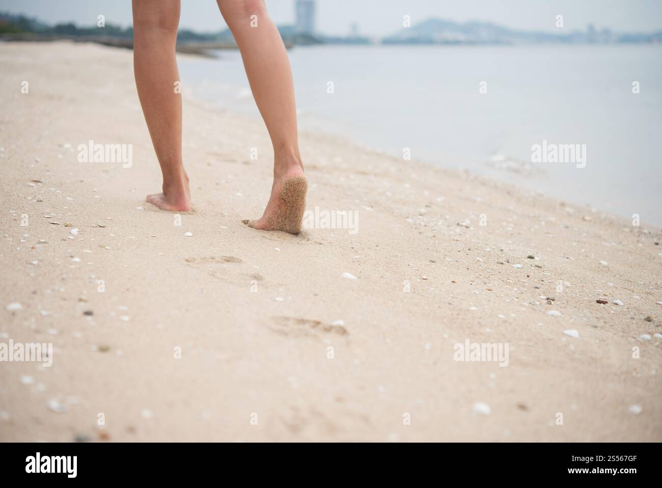 Junge Frau zu Fuß auf Sand Strand hinterlassen Spuren im Sand. Urlaub am Strand genießen. Stockfoto