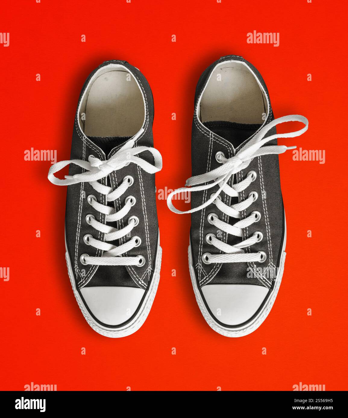 Schwarze Sneakers auf rotem Hintergrund. Schwarze Sneakers auf rotem Hintergrund Stockfoto