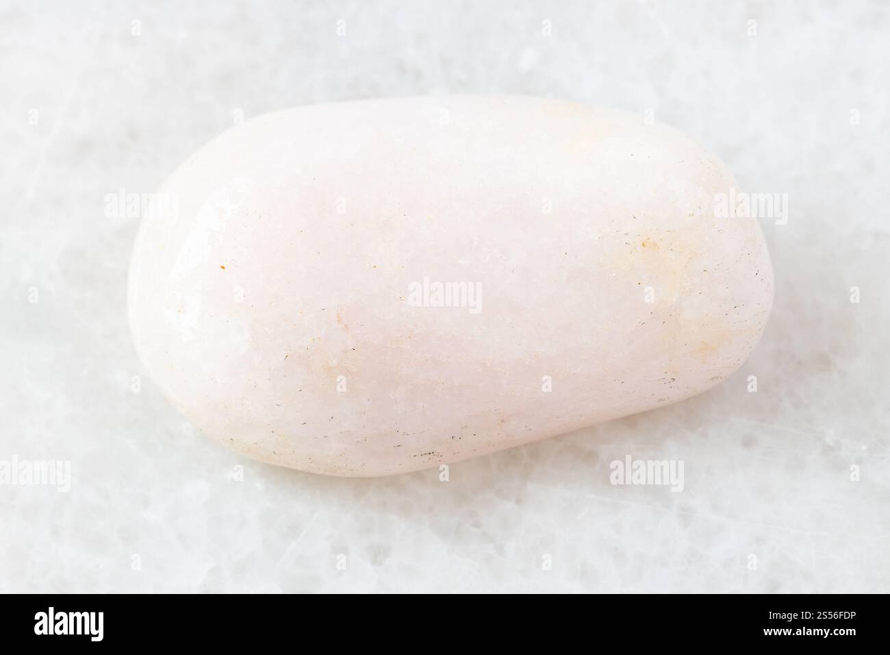 Nahaufnahme der Probe des natürlichen Minerals aus der geologischen Sammlung - Polierter Petalit-Stein auf weißem Marmorhintergrund Stockfoto