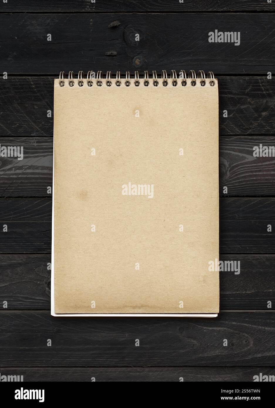 Geschlossenes spiralförmiges Notizbuch auf einem schwarzen Holztisch. Modell. Geschlossenes spiralförmiges Notizbuch auf einem schwarzen Holztisch Stockfoto