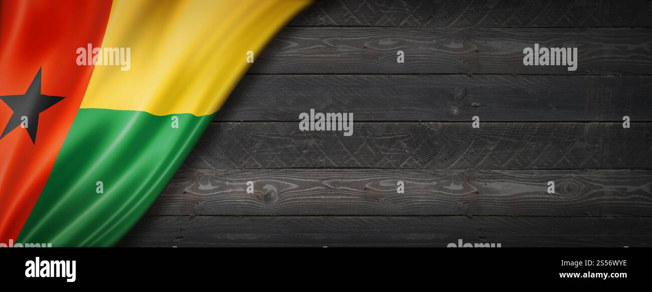 Guinea-Bissau-Flagge auf schwarzer Holzwand. Horizontales Panorama-Banner. Guinea-Bissau-Flagge auf schwarzem Holzbanner Stockfoto