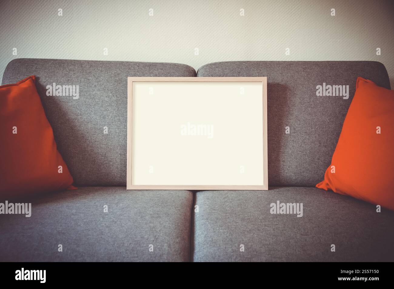 Leerer Bilderrahmen auf einem Sofa. Minimalistischer Innenhintergrund. Leerer Bilderrahmen auf einem Sofa Stockfoto