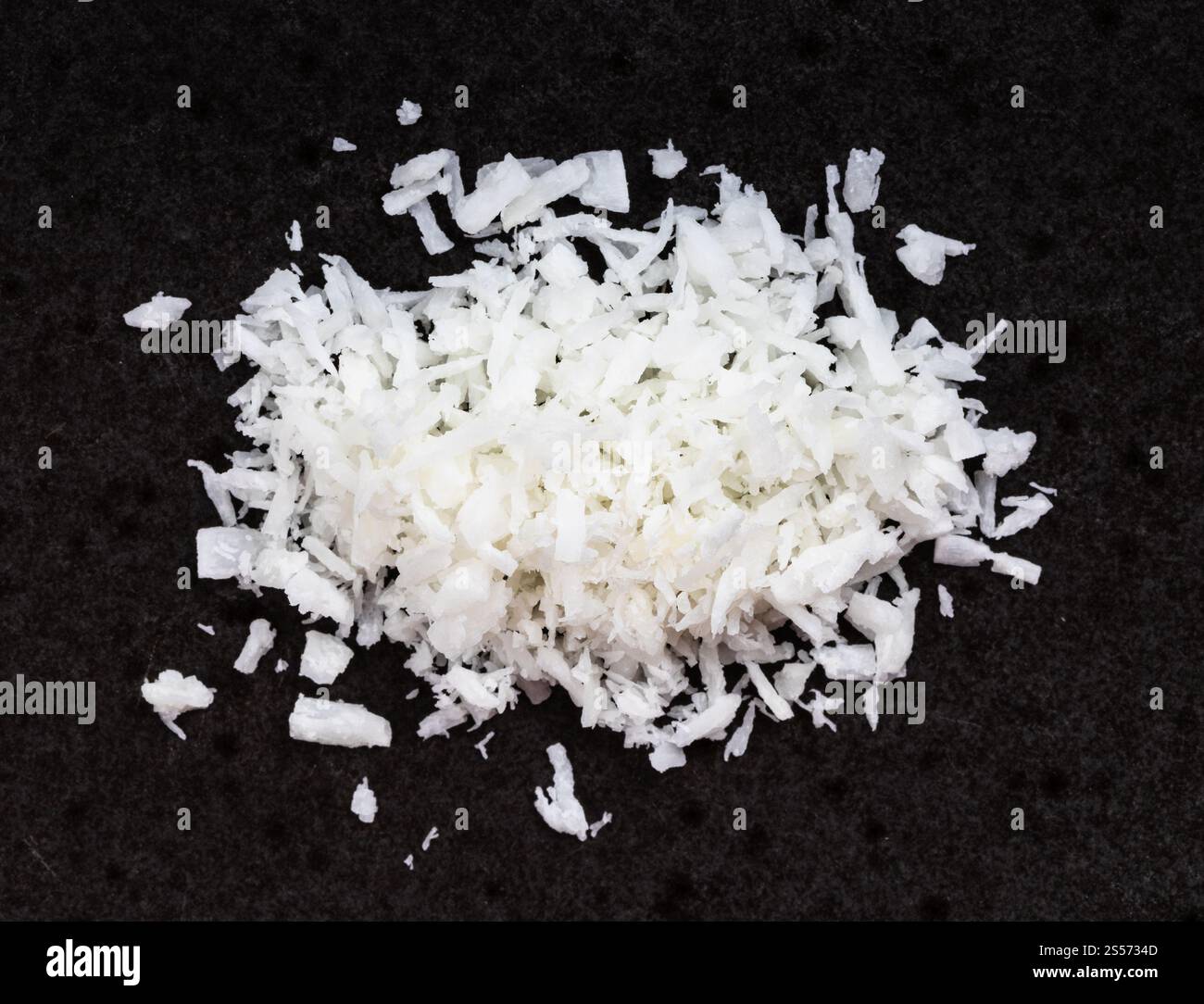 Draufsicht auf den Haufen Kokosflocken aus nächster Nähe Schwarze Keramikplatte Stockfoto