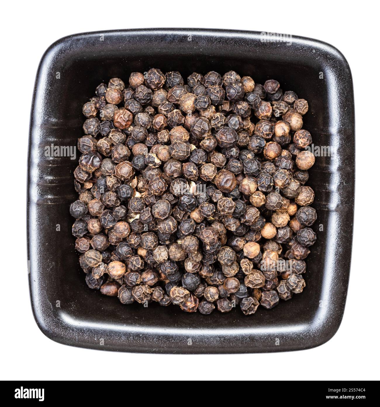 Draufsicht auf schwarze Pfefferkörner in schwarzer Schale isoliert Auf weißem Hintergrund Stockfoto