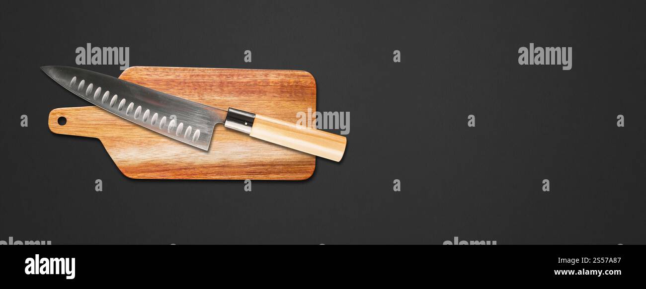 Traditionelles japanisches gyuto Chefmesser auf einem Schneidebrett. Schwarzer Banner-Hintergrund Stockfoto