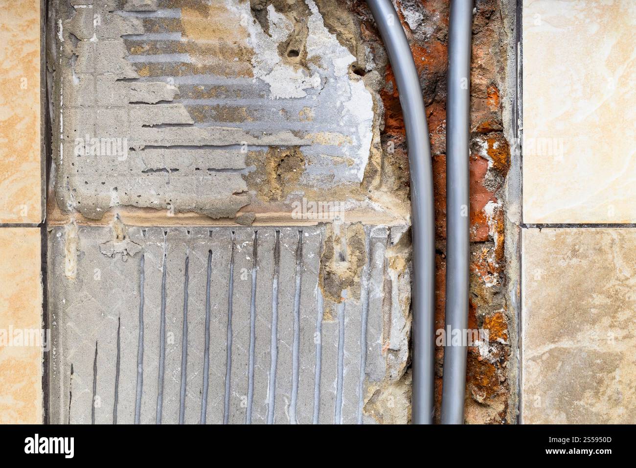 Neue Wasserrohre aus Polyethylen hoher Dichte in der Ziegelwand mit entfernten Keramikfliesen aus der Wand schließen sich zu Hause an Stockfoto