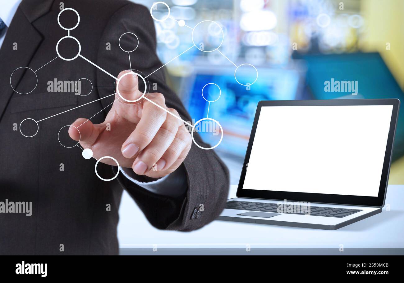 Geschäftsmanns Hand zeigt leere Flussdiagramme und leeren Laptop-Computer im Ladenhintergrund als Konzept Stockfoto