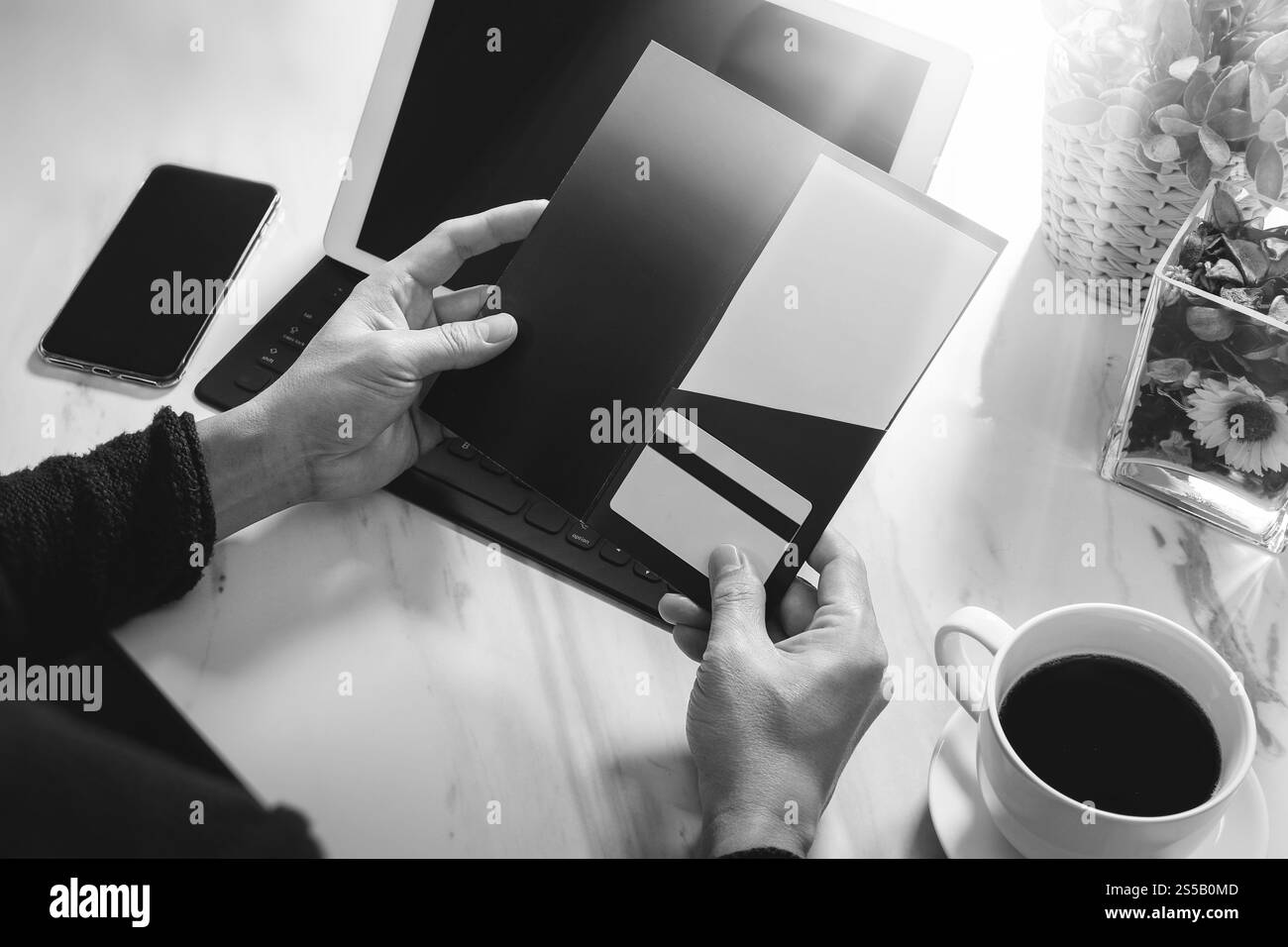 Geschäftsleute Hände halten neue Geschenkkarte oder Kreditkarte, Digital Tablet Computer Dock Tastatur, Smartphone auf Marmorschreibtisch, schwarz weiß Stockfoto