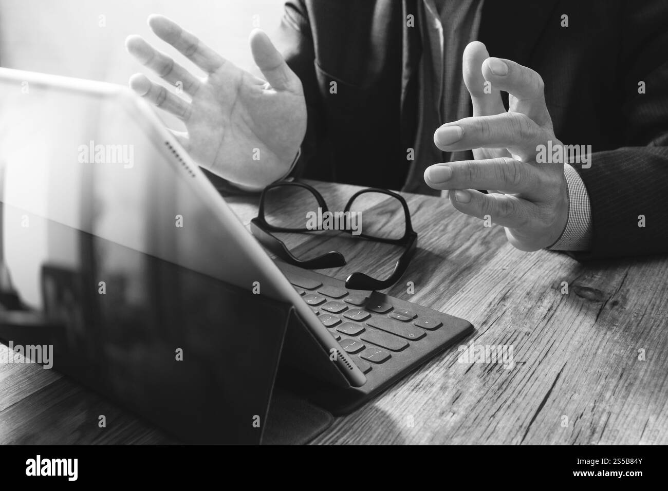 Erfolg Geschäftsmann Hand mit Brillen, digital-Tablette Docking-smart-Tastatur auf Holz Schreibtisch, schwarz weiß Stockfoto