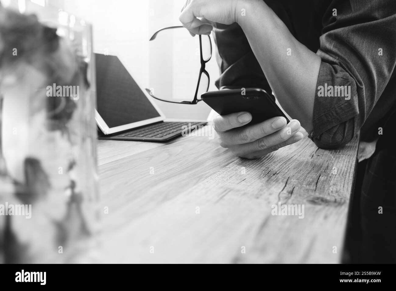Geschäftsmann Hand mit Brillen mit smart-Phone, mobile Zahlungen online-shopping, Omnichannel, digital-Tablette Docking-Tastatur Computer, Blume Glas Stockfoto