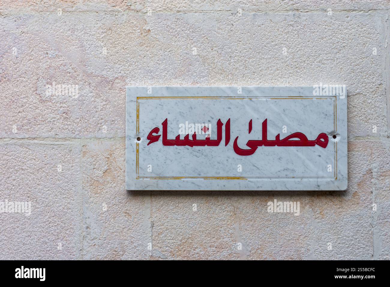 Ein Marmorschild mit roter arabischer Schrift „Gebetsraum für Frauen“ auf einer Steinmauer. Stockfoto