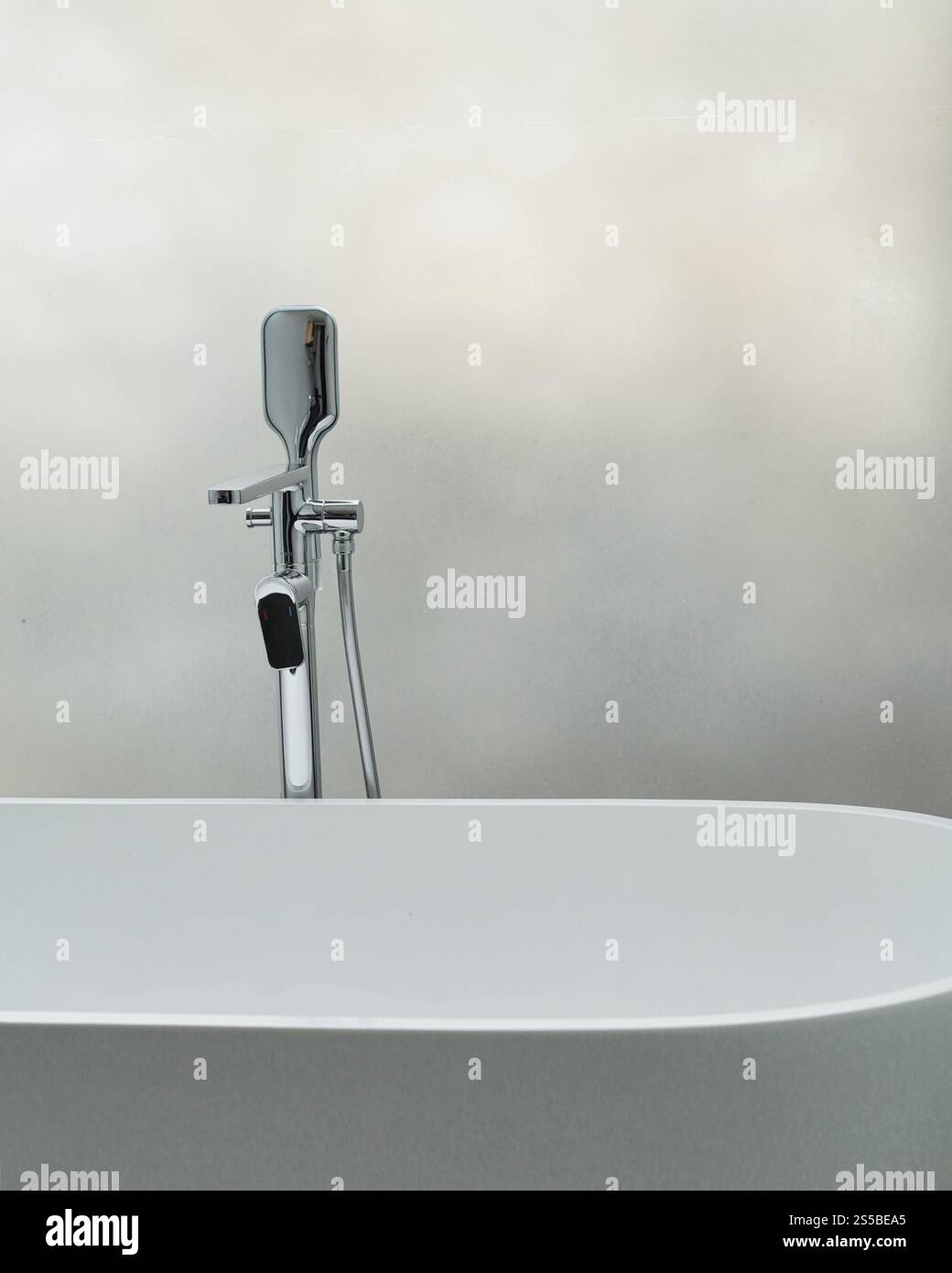 Nahaufnahme eines Chromhahns neben einer weißen Keramikbadewanne Stockfoto