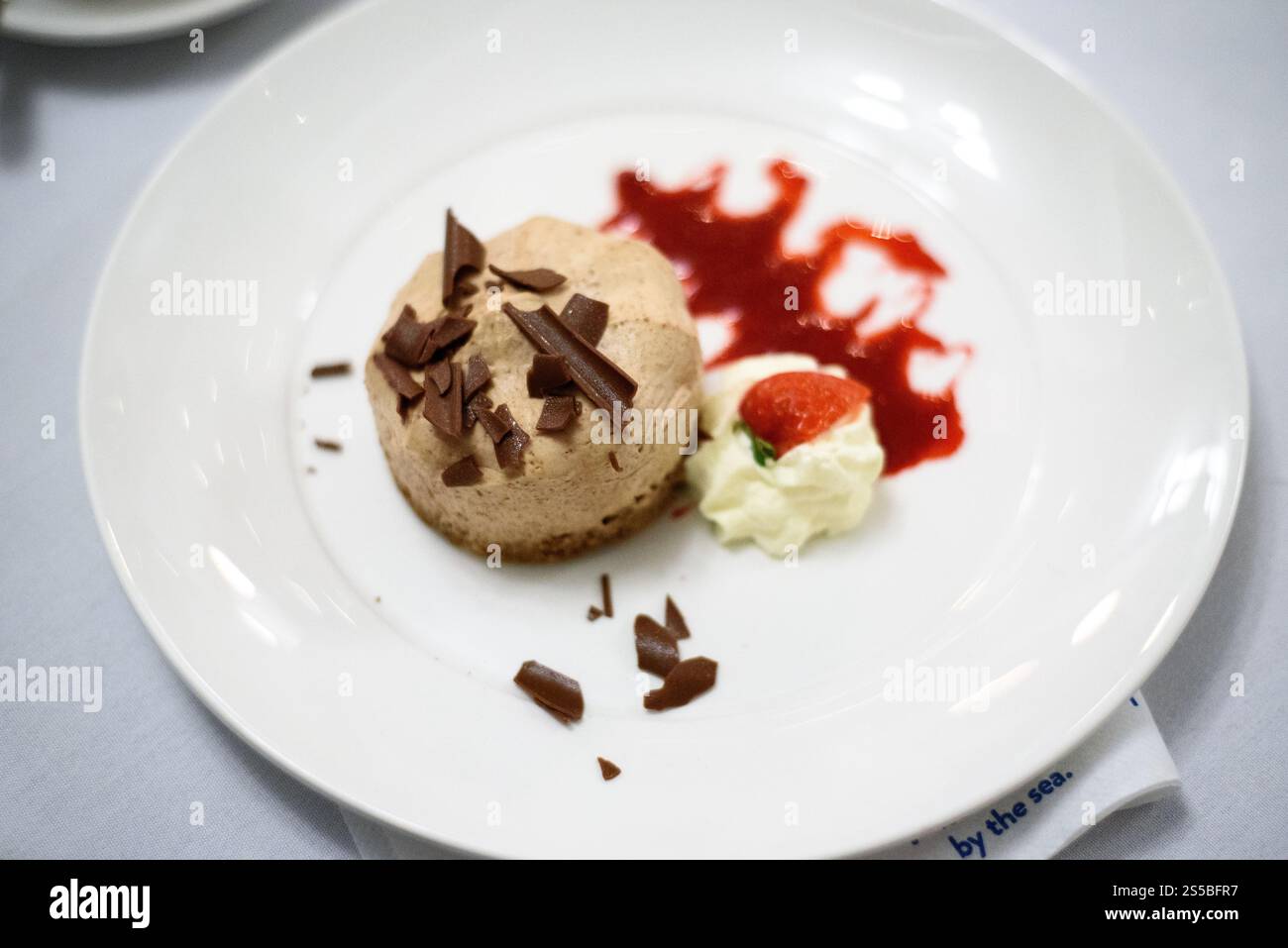 Nahaufnahme eines Schokoladeneis-Desserts mit Schlagsahne und Frucht-Coulis-Sauce Stockfoto