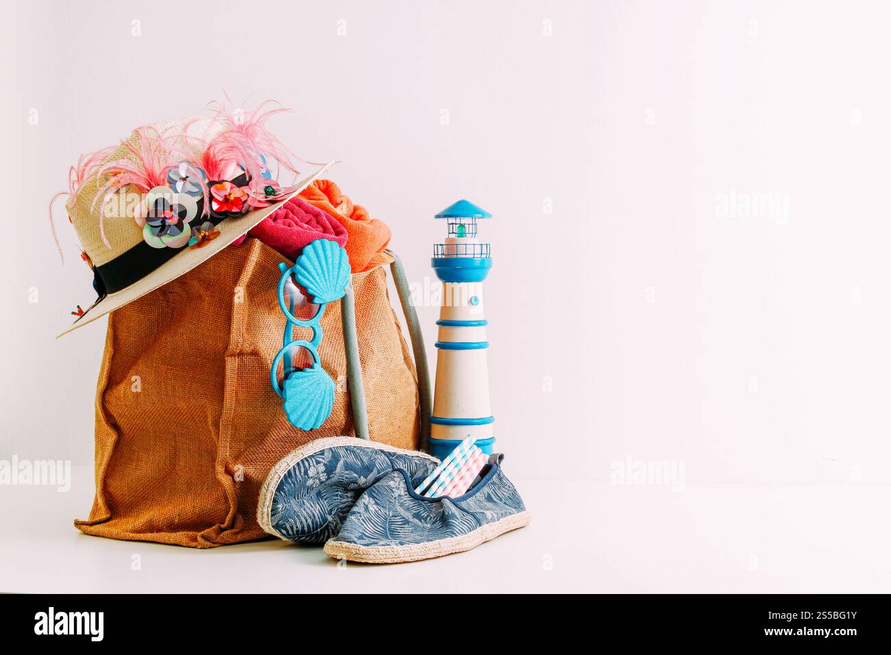 Reisekonzept für Sommerurlaub. Hipster-Strandtasche mit Artikeln für einen Tag am Meer auf weißem Hintergrund Stockfoto