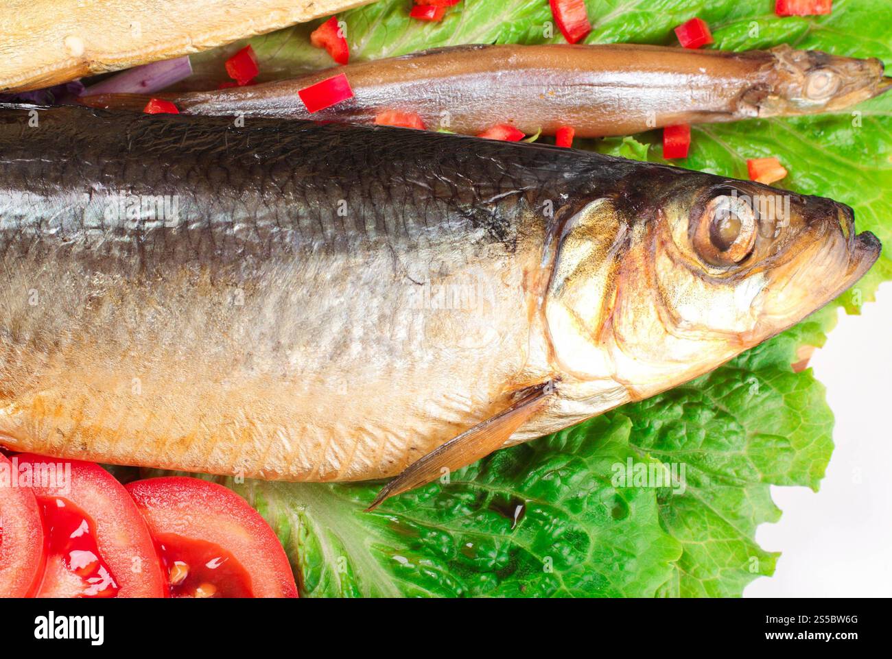 Fisch auf Teller mit rotem Pfeffer isoliert auf weißem Hintergrund. Fisch auf Teller mit rotem Pfeffer Stockfoto