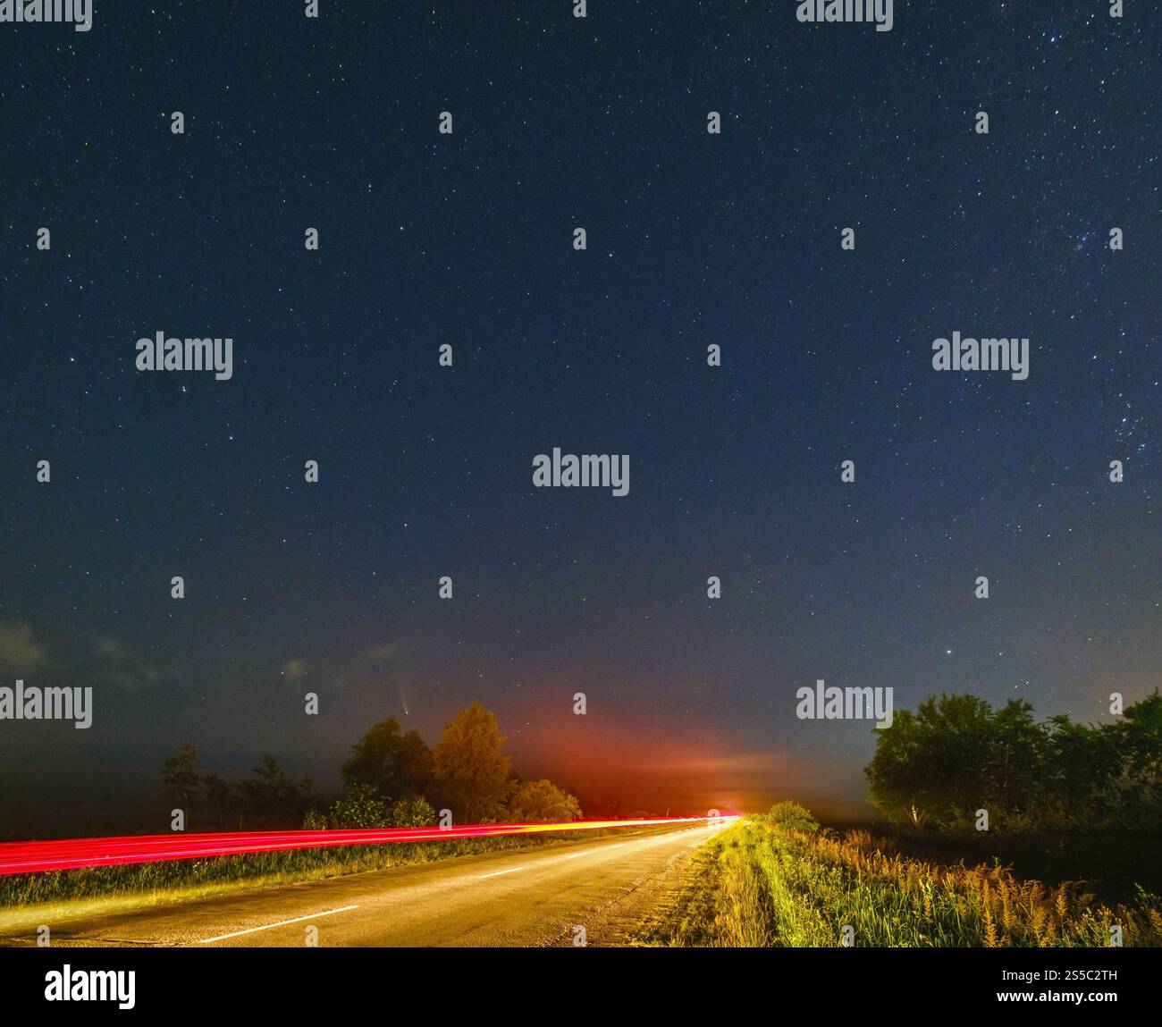 Komet Neowise C2020 F3, wie er im Sommerhimmel über einer Wiese in der Nähe der Landstraße, Region Lviv, Ukraine fliegt. Stockfoto