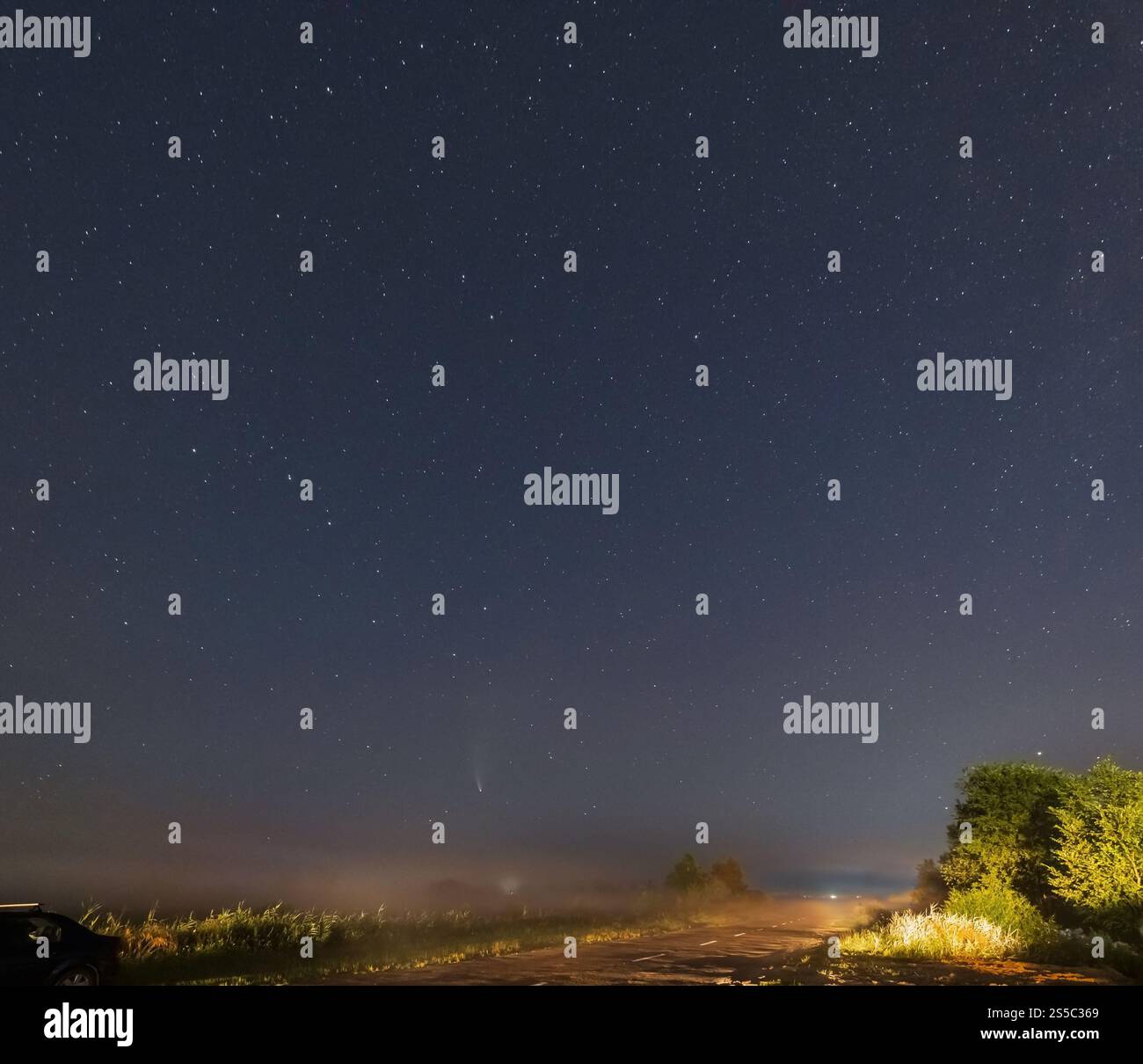 Komet Neowise C2020 F3, wie er im Sommerhimmel über einer Wiese in der Nähe der Landstraße, Region Lviv, Ukraine fliegt. Stockfoto