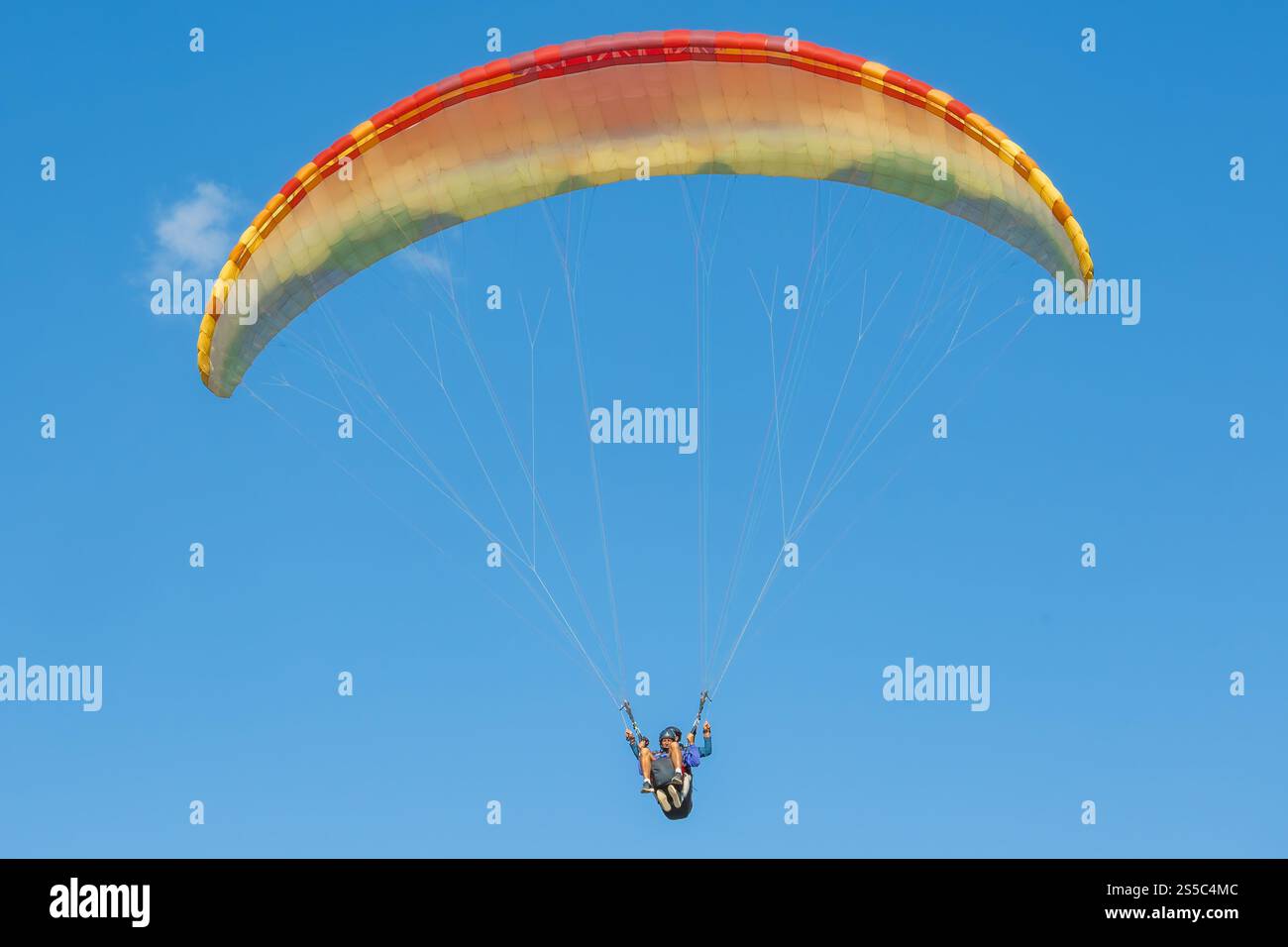 Ein farbenfroher Gleitschirm gleitet mühelos durch den Himmel. Stockfoto