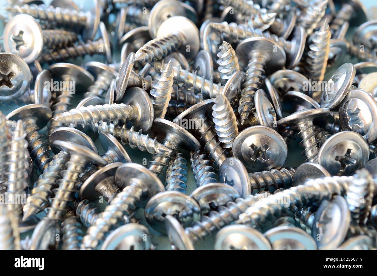 Viele kleine silberne Schrauben sind in einem großen chaotischen Haufen. Makroansicht Nahaufnahme. Viele kleine silberne Schrauben sind in einem großen chaotischen Haufen Stockfoto