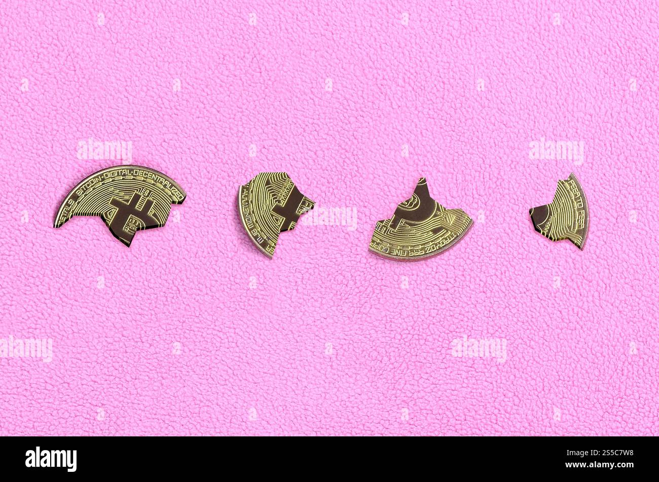 In Stücke zerbrochen Bitcoin auf einem rosafarbenen Vliesstoff-Hintergrund. Der Fall und der Zusammenbruch des Kurses der Kryptowährung. Schlechte Nachrichten für Stockfoto