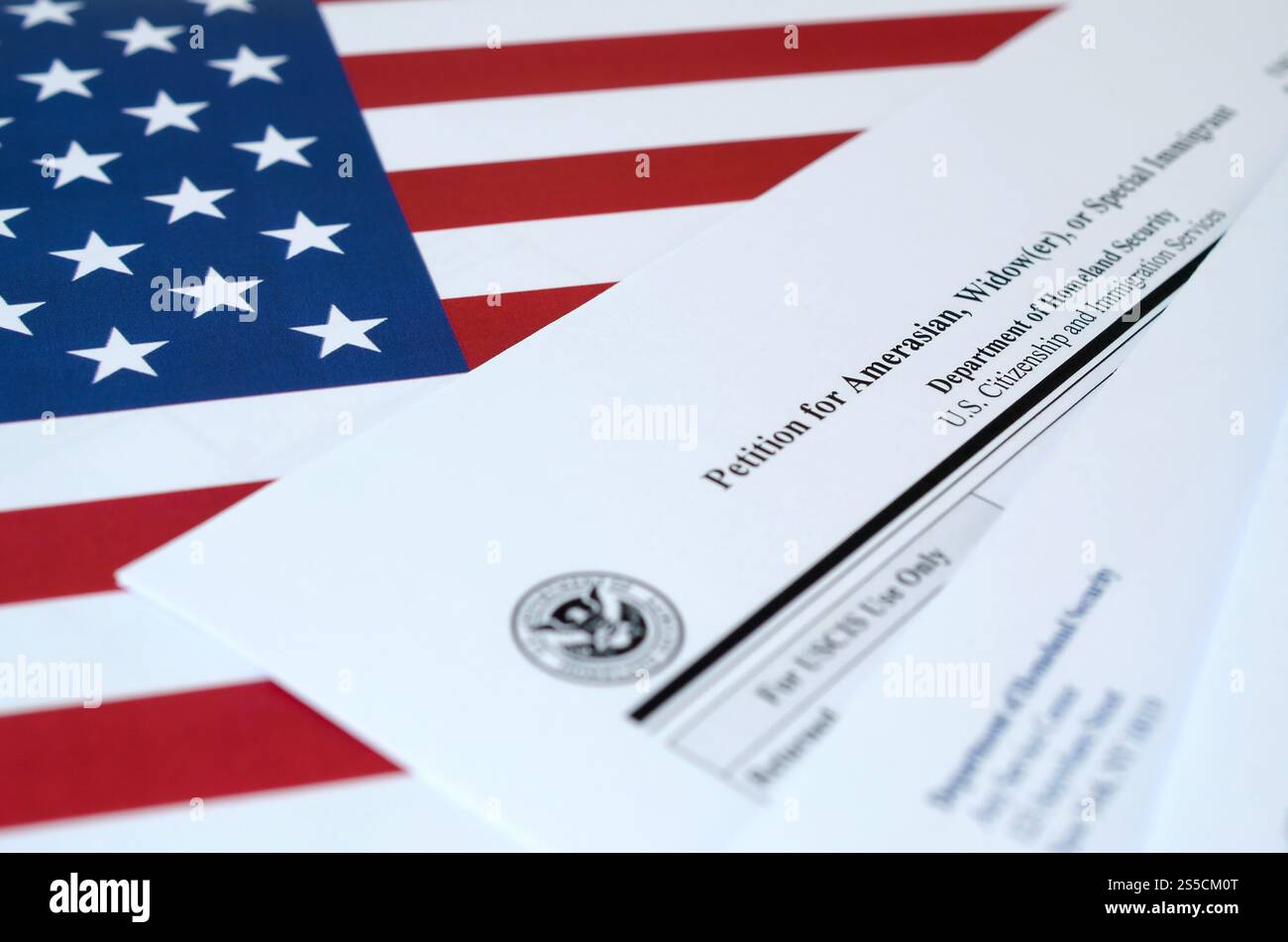 Die I-360 Petition für ein unbeschriftetes Formular für Amerasianer, Witwer oder spezielle Einwanderer liegt auf der Flagge der Vereinigten Staaten mit Umschlag vom Department of Homeland Security Stockfoto