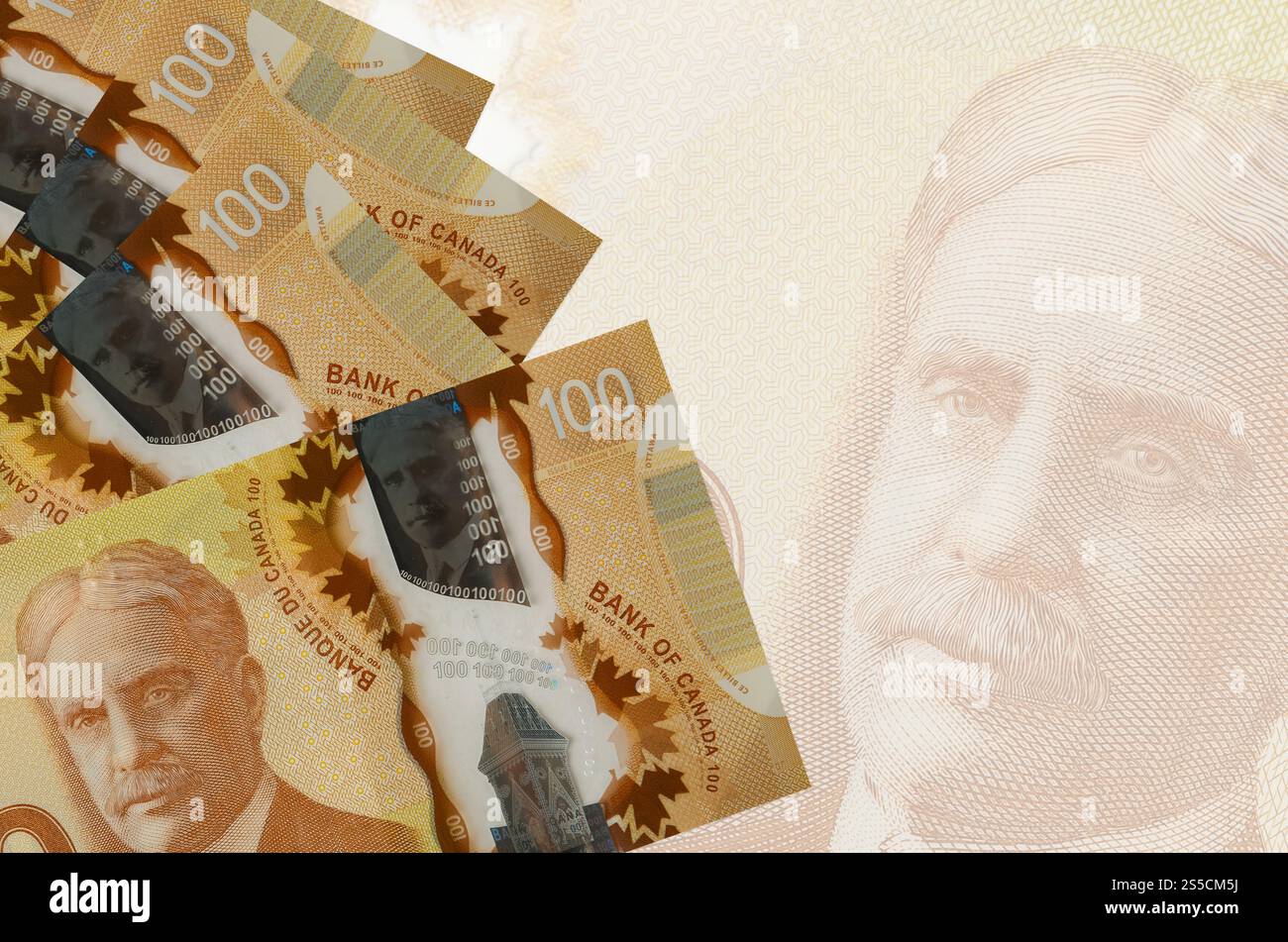 100 kanadische Dollarscheine liegen auf dem Hintergrund großer halbtransparenter Banknoten. Abstrakter Geschäftshintergrund mit Kopierraum. 100 Kanadier Stockfoto