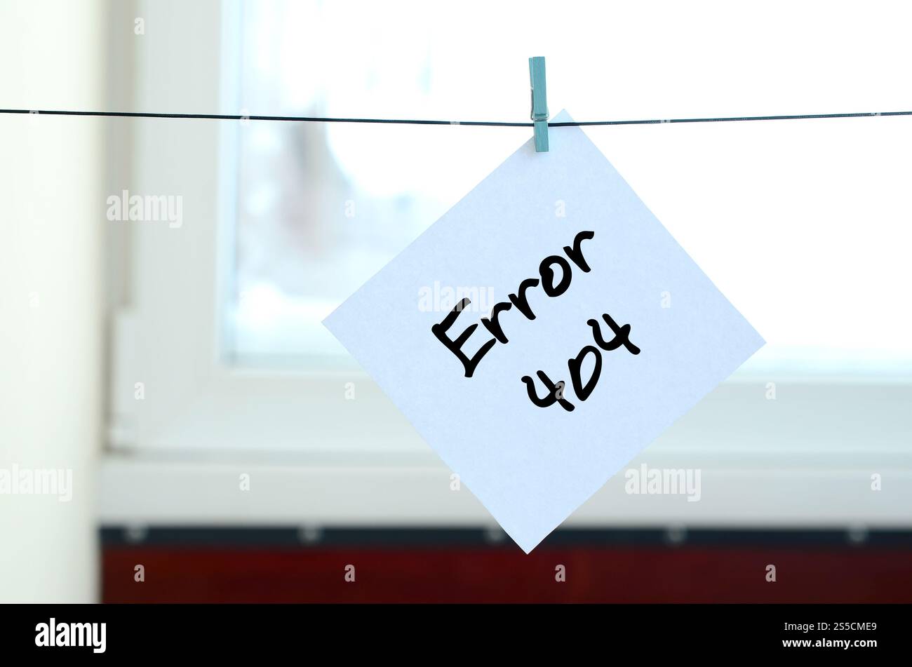 Fehler 404. Die Notiz ist auf einem weißen Aufkleber geschrieben, der mit einer Wäscheklammer an einem Seil auf einem Hintergrund aus Fensterglas hängt Stockfoto
