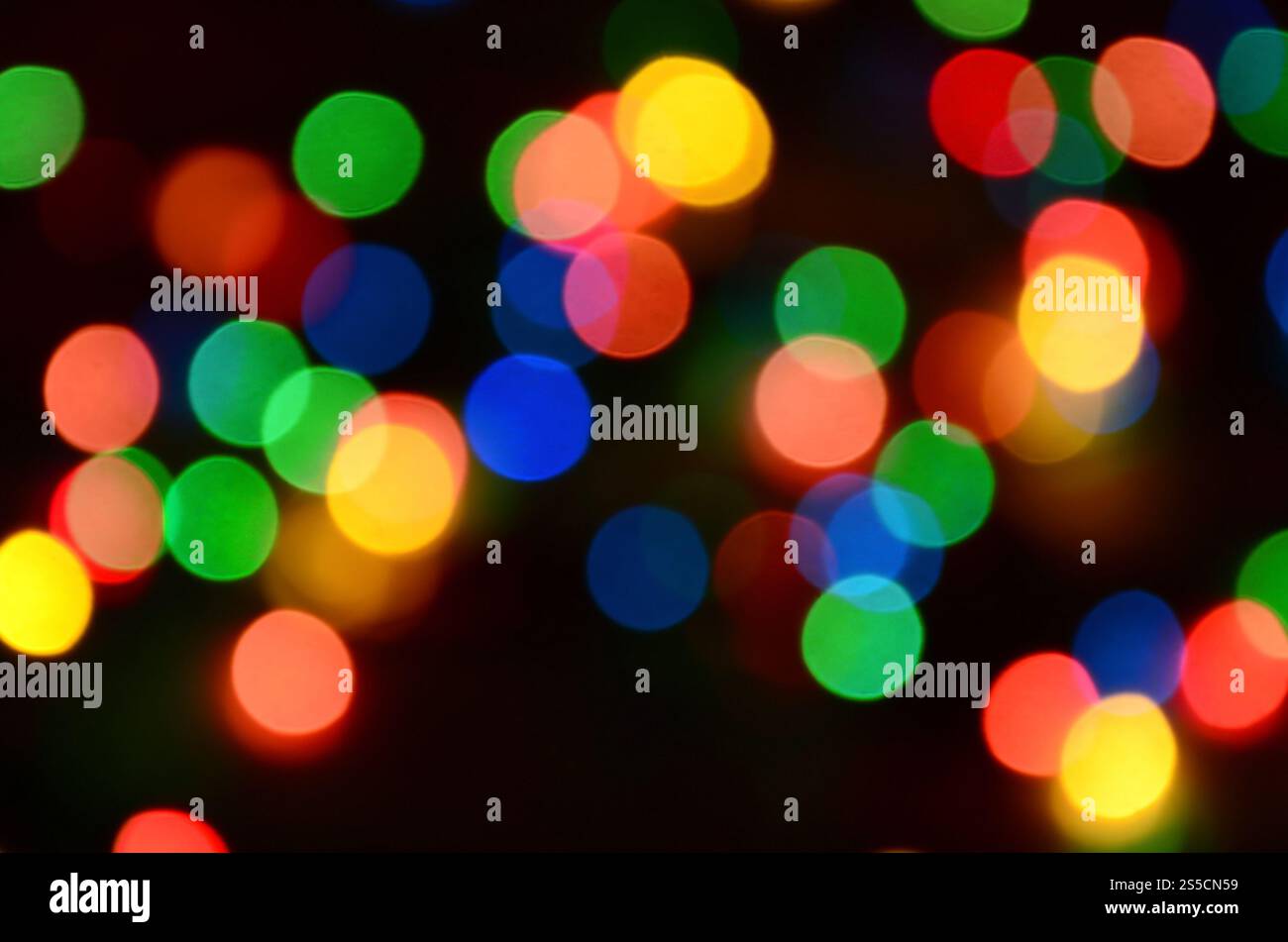 Verschwommene festliche bunte Lichter über Schwarz als Hintergrund nützlich. Alle Hauptfarben enthalten. Rot, Gelb, Grün und Blau Stockfoto