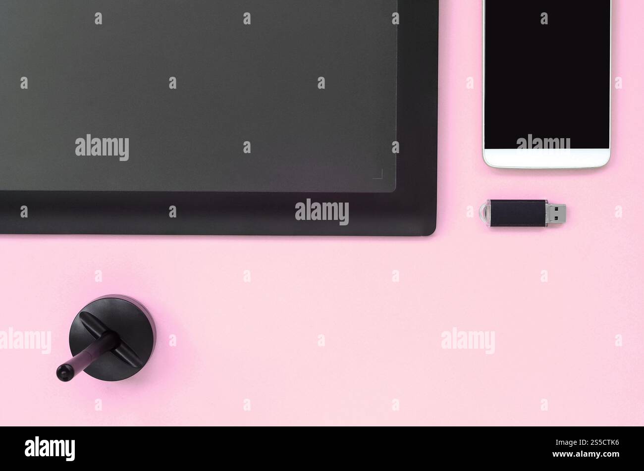 Grafiktablett und Stift für Illustratoren und Designer liegen mit USB-Speicherkarte und Smartphone auf pastellrosa Hintergrund. Flaches Design. Oben Stockfoto