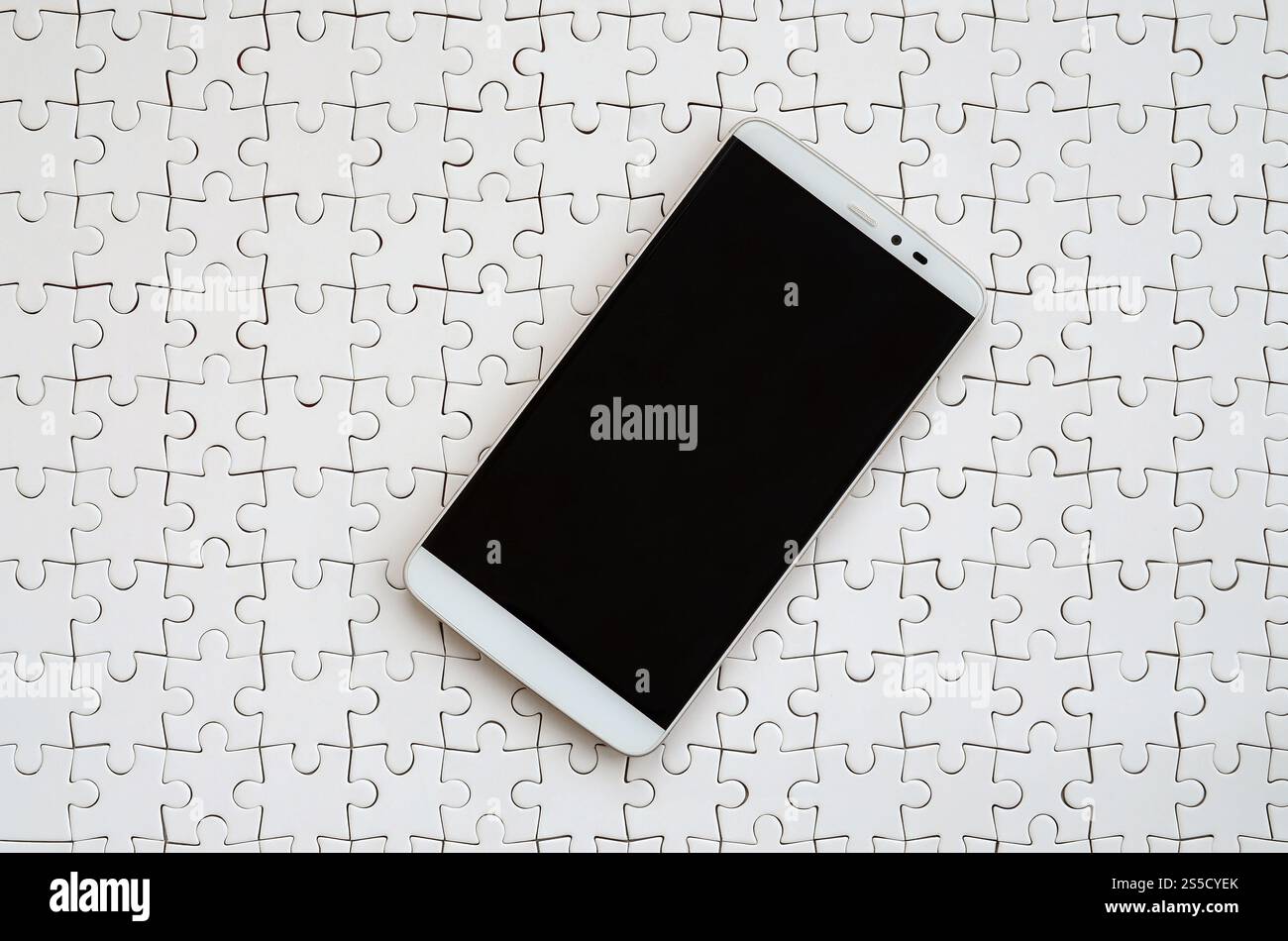 Eine moderne grosse Smartphone mit Touchscreen liegt auf einem weißen Puzzle im zusammengebauten Zustand Stockfoto