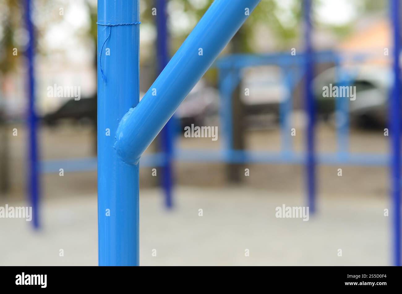 Blaue Metallrohre und Querstangen vor einem Straßensportplatz für Leichtathletik-Training. Sportgeräte im Freien. Makrofoto mit selektiv Stockfoto