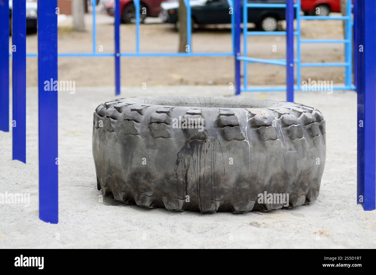 Ein großer schwarzer Reifen vor einem Straßensportplatz für Leichtathletik- und Crossfit-Training. Sportgeräte im Freien. Makrofoto Stockfoto