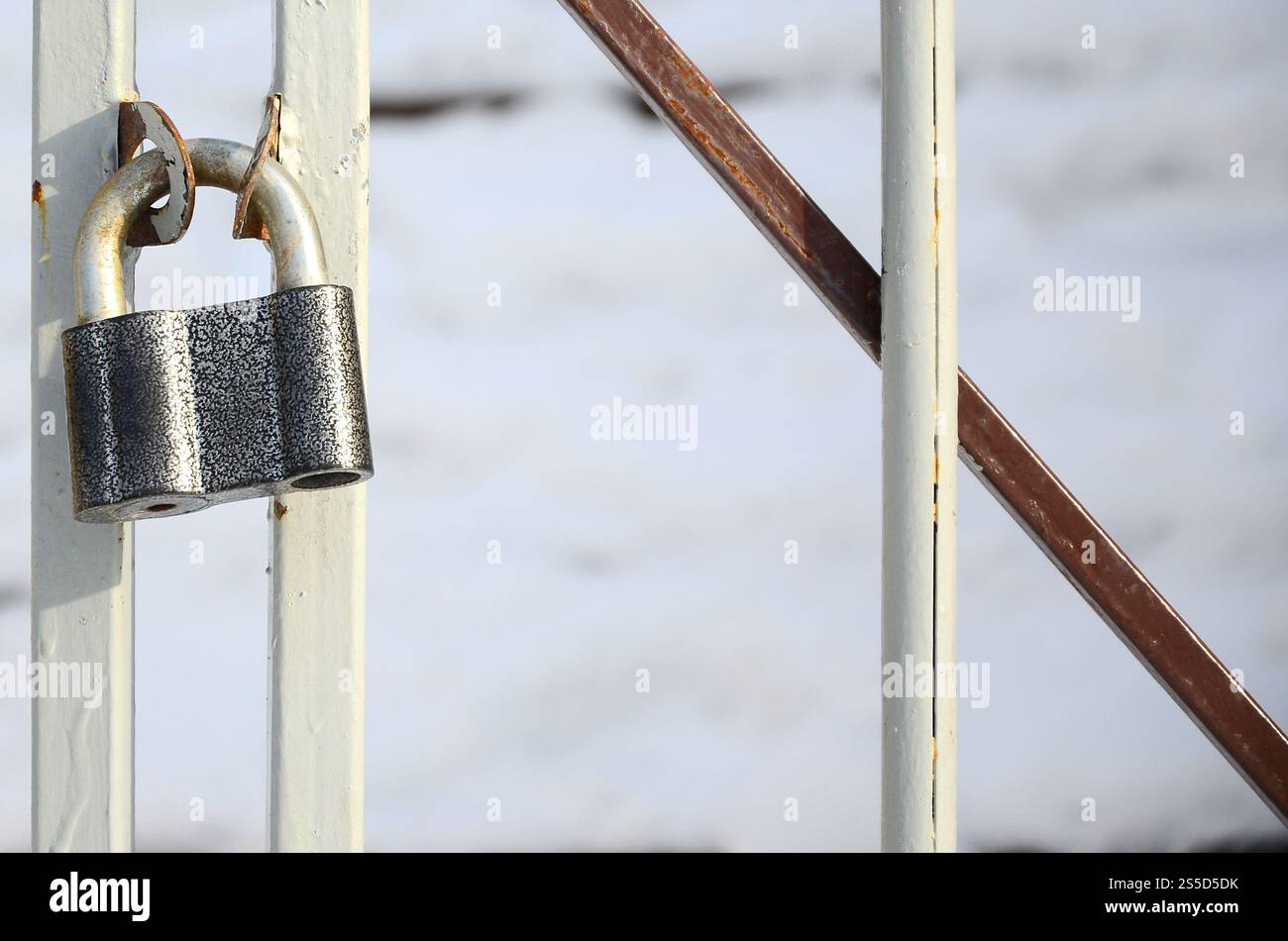 Ein großes graues Vorhängeschloss hängt an einem Metalltor Stockfoto